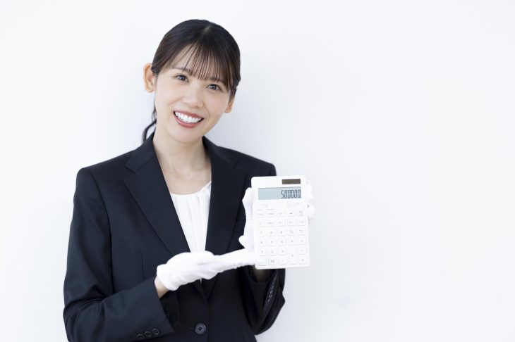 笑顔で電卓の数字を見せている女性査定士