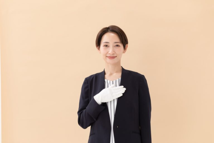 胸に手を当てる白い手袋をはめた女性