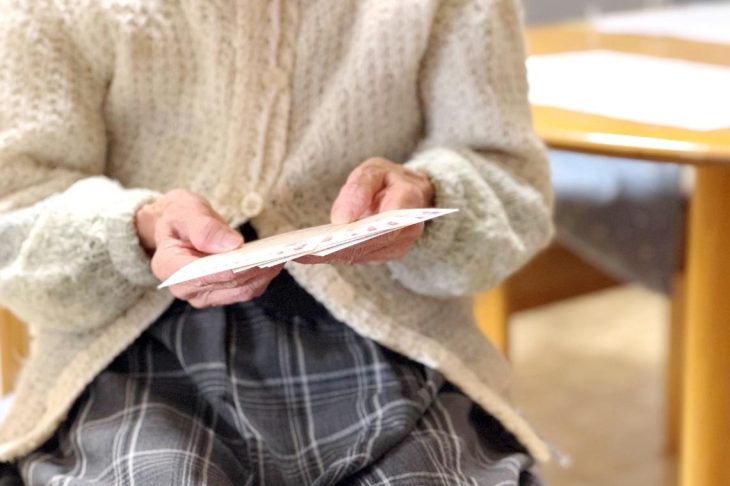 数枚のはがきを手に持っている女性
