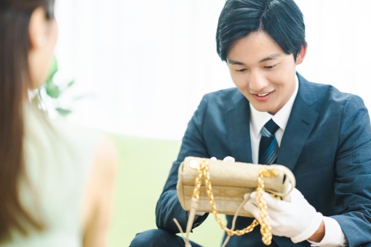 バッグを持ち込んだ女性と、そのバッグを手に取り査定する男性