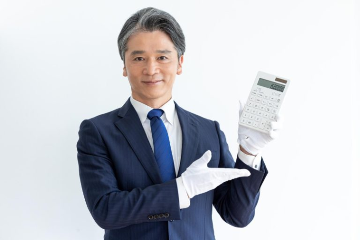 白い手袋をはめて電卓で金額を提示する査定士風の男性
