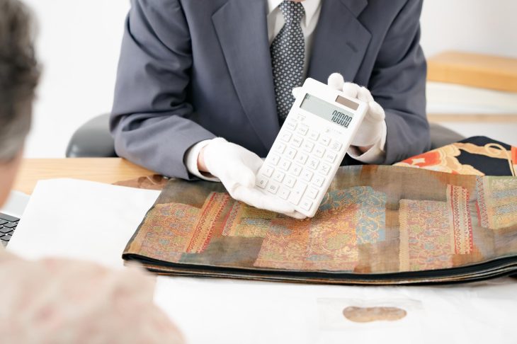 着物の査定後、電卓で買取価格を提示する査定士の手元