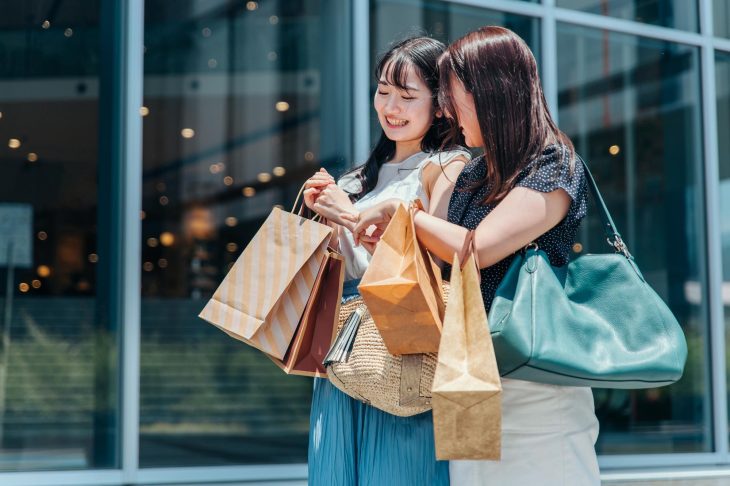 たくさんのショッピングバッグを持って、買い物を楽しむ2人の女性