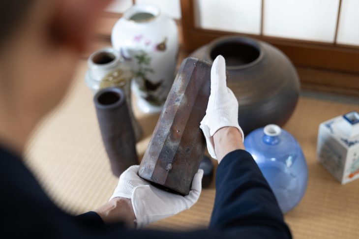 骨董品を査定している人と背後にあるさまざまなアイテム