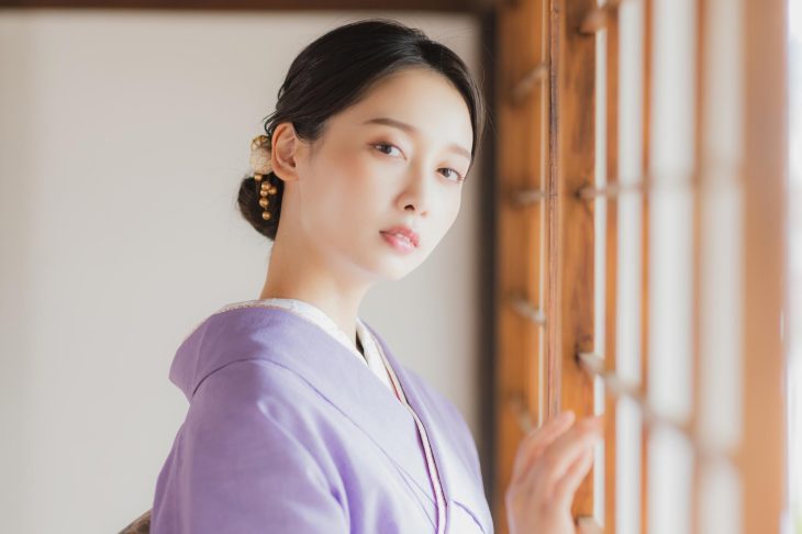 淡い紫色の着物を着て髪をまとめ、和風の髪飾りを着けた女性