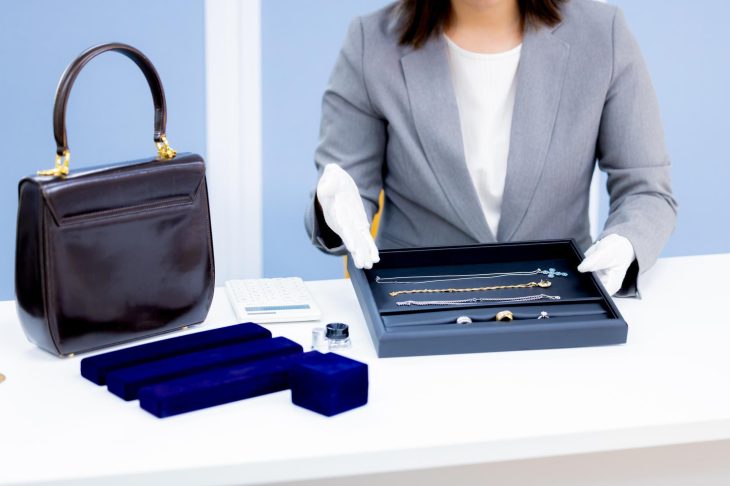 ブランドバッグやジュエリー一式を査定する女性
