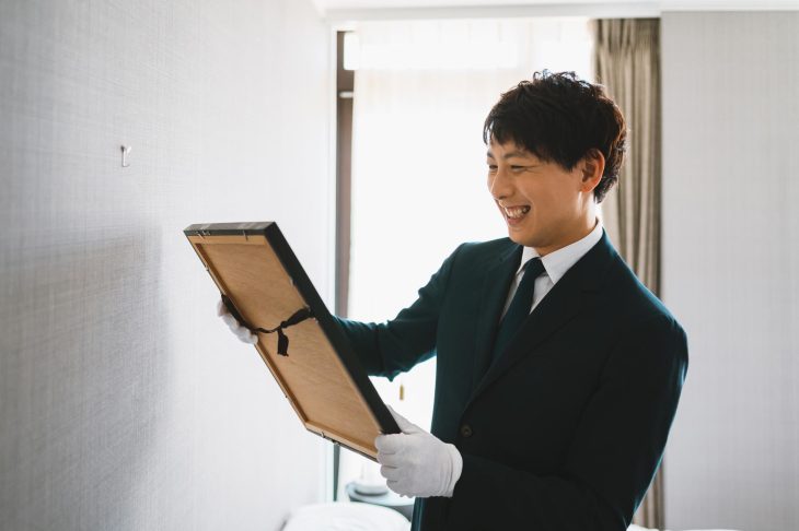 絵画を手に取って確認している笑顔の男性