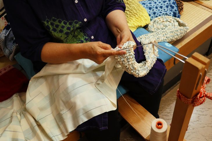 着物の生地に手作業で絞りを施す女性