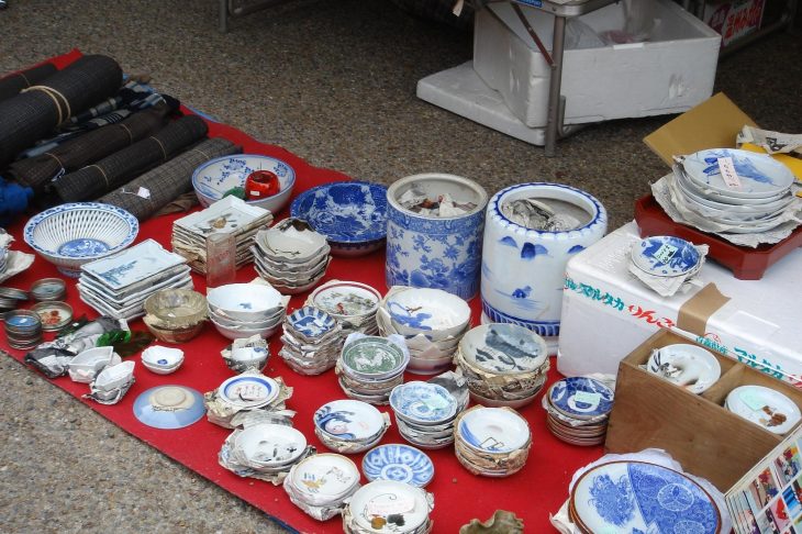 赤い布の上に並べられている大量の骨董品