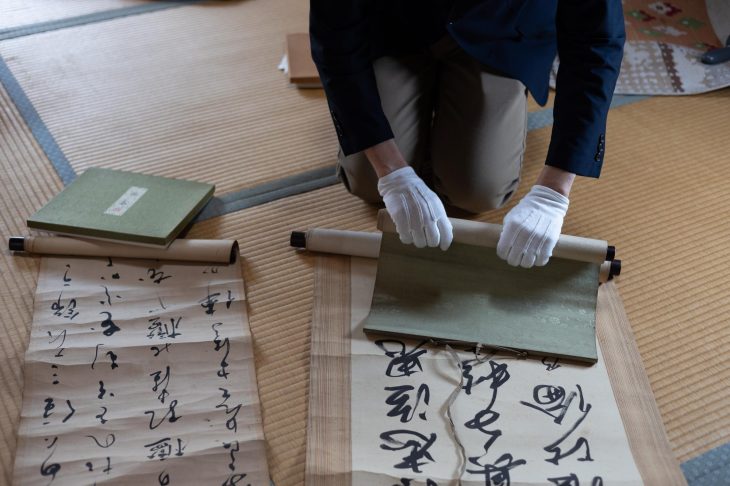 軸棒を使って掛け軸を巻き取る手元
