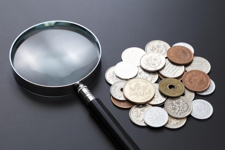 さまざまな日本の硬貨と虫眼鏡
