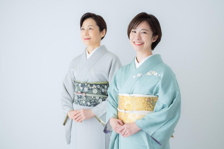 淡い色合いの着物を着て、笑顔で並ぶ2人の女性